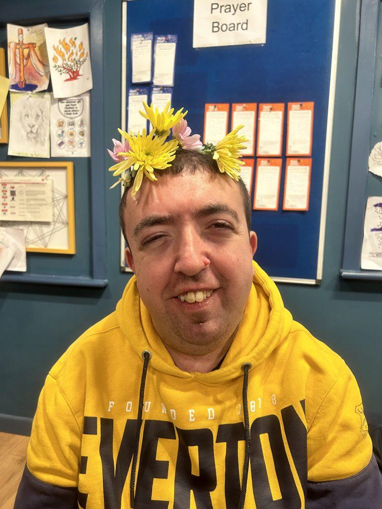 Man with yellow hoodie and flowers in hair